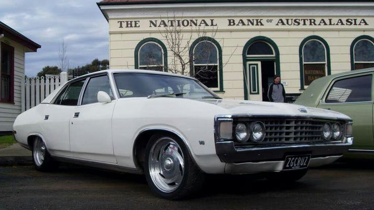 an old white car parked in front of a building