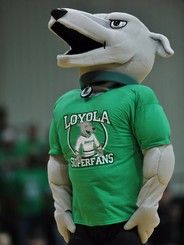 the mascot is wearing a green shirt and has his mouth open while standing in front of an audience