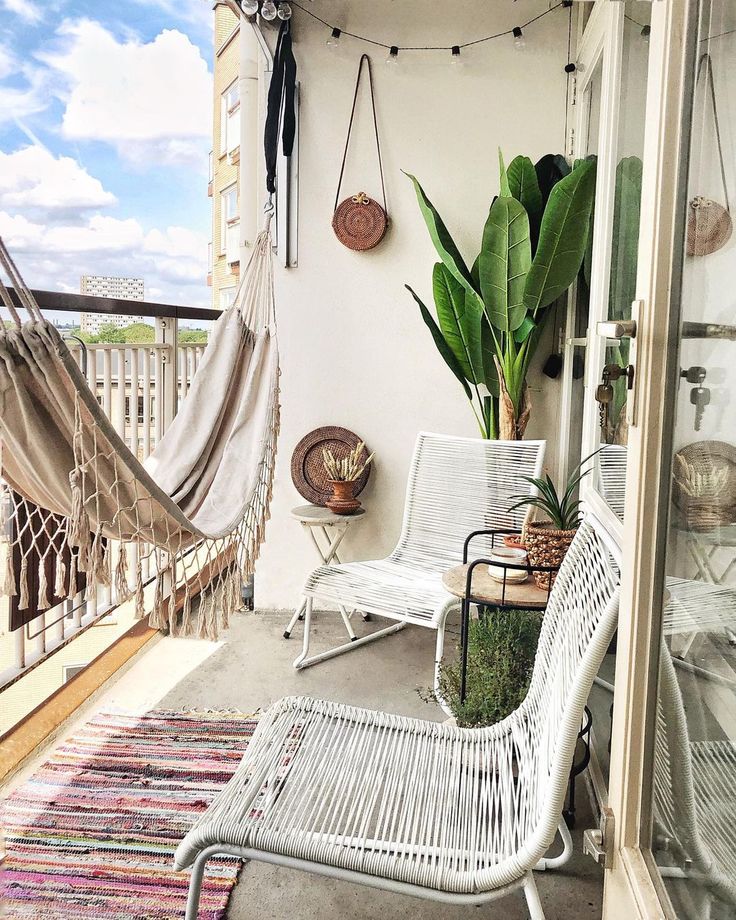 a balcony with hammock, chairs and potted plants