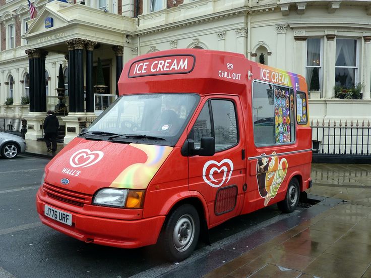 a red ice cream truck parked in front of a building