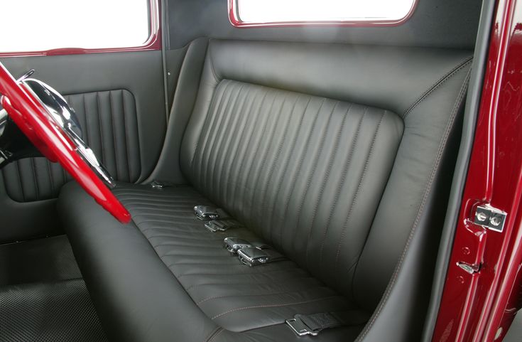 the interior of an old car with red trim and black leather upholstered seats