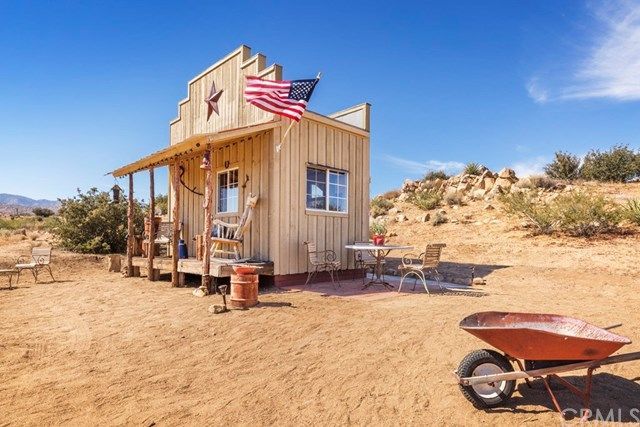 a small wooden building with an american flag on the roof and a wheelbarrow