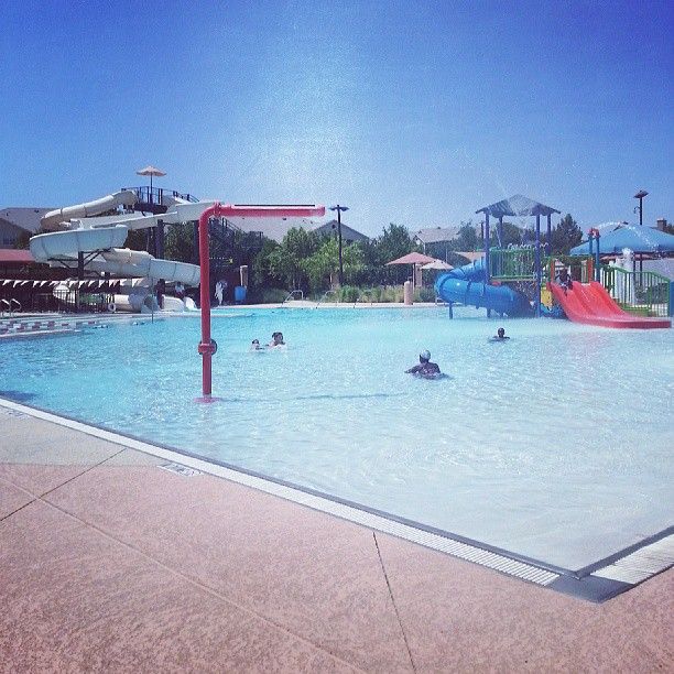 people are playing in the water at an outdoor swimming pool with slides and waterslides