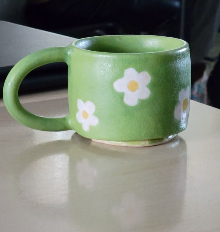 a green coffee cup with white flowers on it