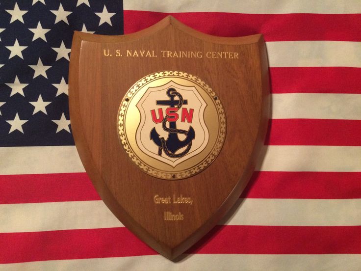 a wooden plaque with the u s naval training center on it in front of an american flag