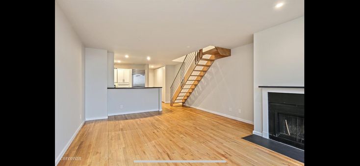 an empty living room with hardwood floors and stairs