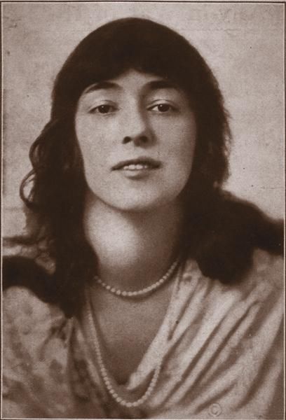 an old black and white photo of a woman with long hair wearing a pearl necklace