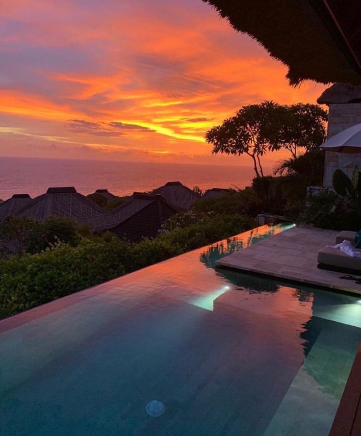 the sun is setting over an outdoor swimming pool