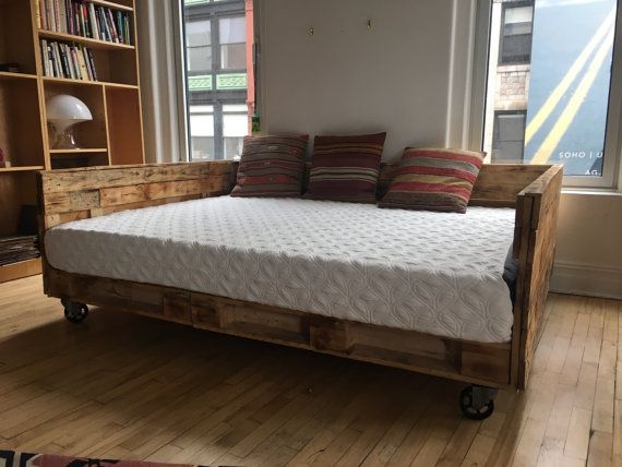 a bed made out of wooden pallets in front of a window with bookshelves