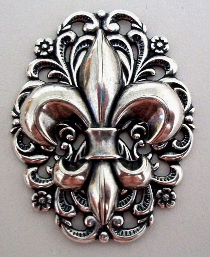 a metal fleur de lis on a white wall in the shape of a mask