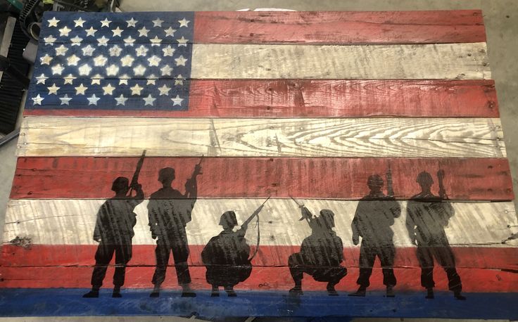 an american flag painted on wood with silhouettes of soldiers