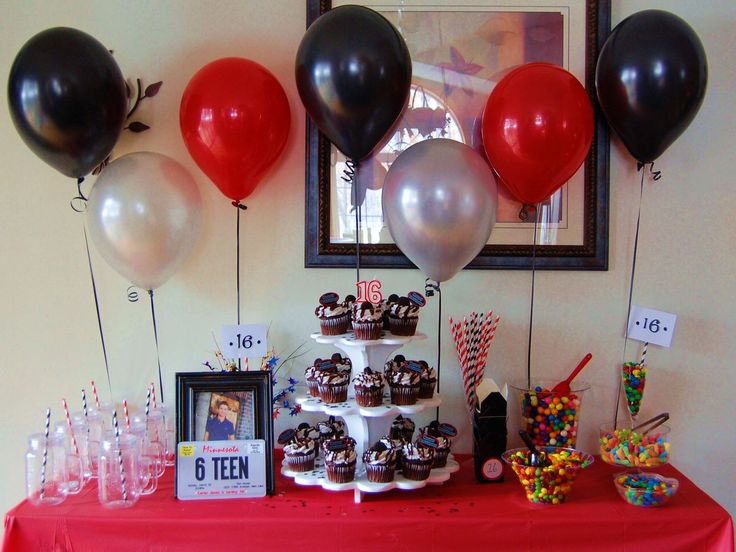 a table topped with lots of cupcakes and balloons