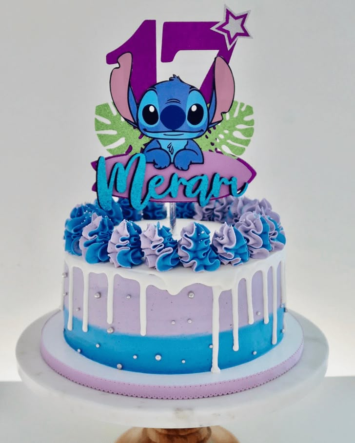 a blue and purple cake with the number five on it's top is sitting next to a cookie