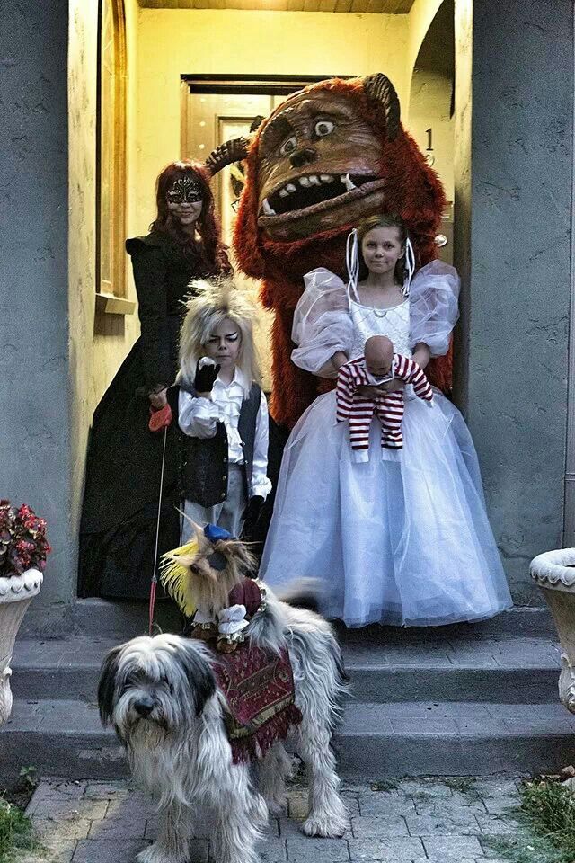 three children in costumes standing on the steps with their dog and costumed monster behind them