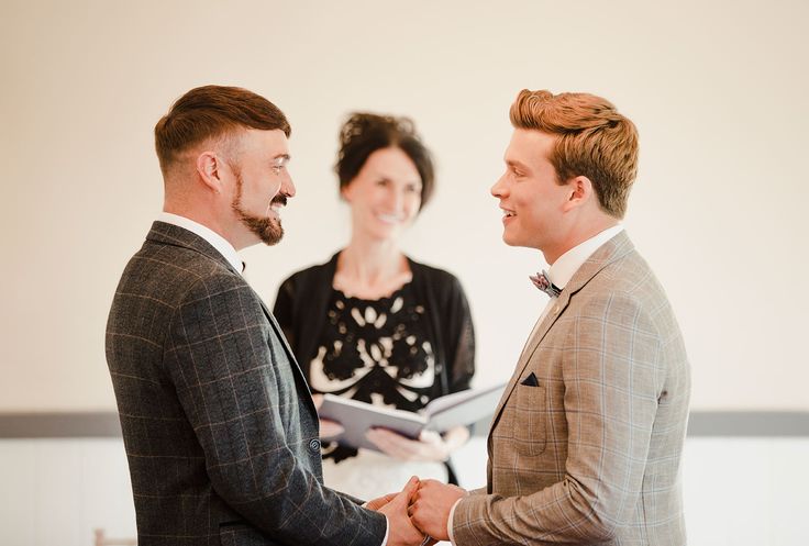 two men are shaking hands while another man is reading the bible in front of them