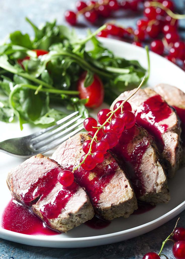 meat with cherry sauce and greens on a plate