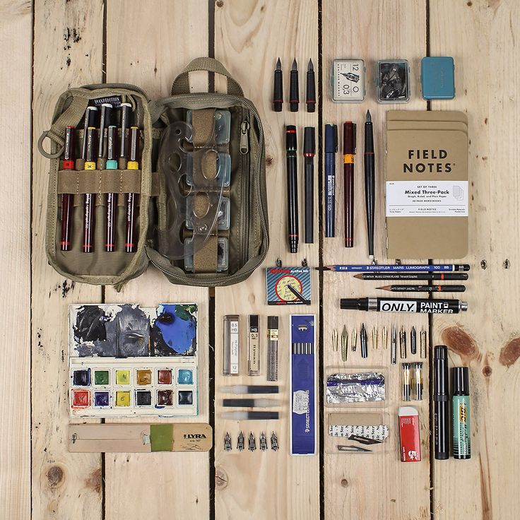 an assortment of art supplies laid out on a wooden table with writing utensils