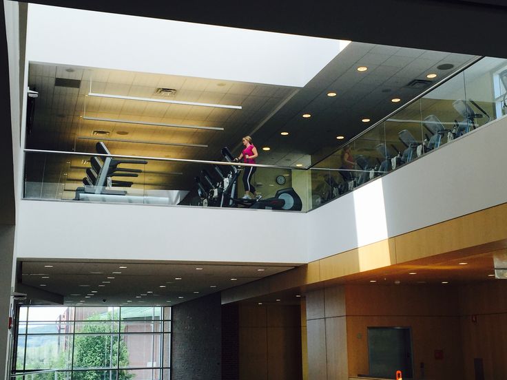 a woman is walking up the stairs in an office building with glass balconies