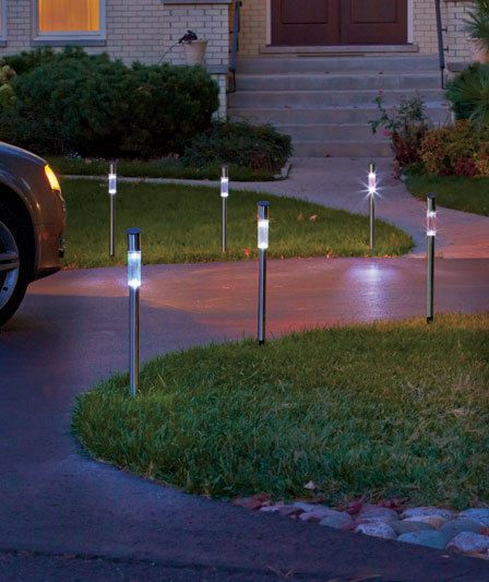 a car parked in front of a house with lights on it's side walk