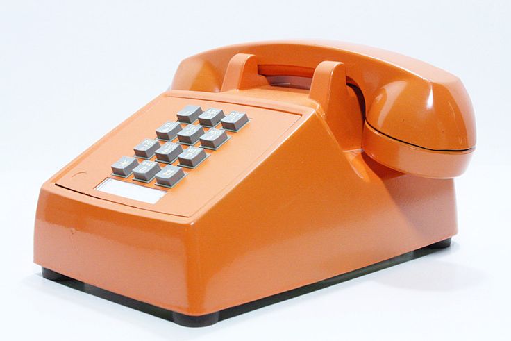 an orange telephone sitting on top of a white table