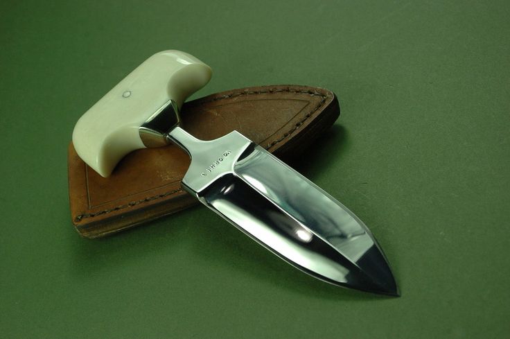 a knife is laying on top of a leather case with a razor blade sticking out of it