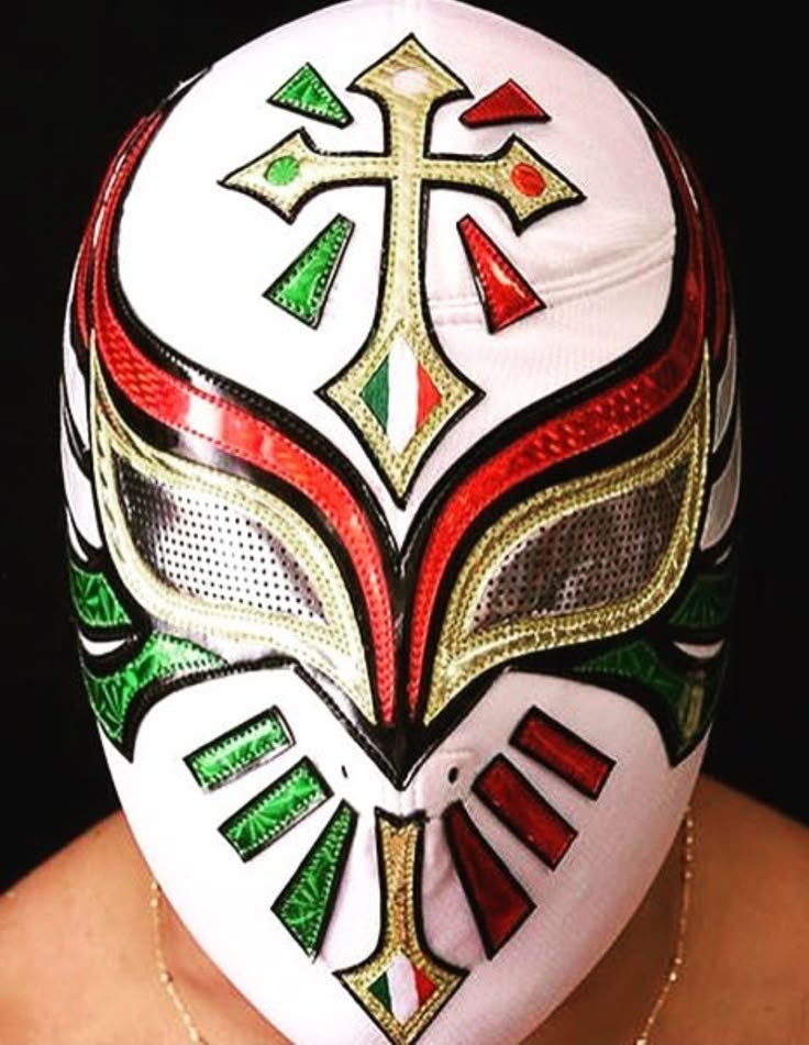 a woman wearing a white mask with red, green and gold designs on it's face