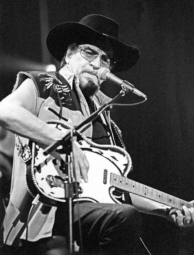 a man with a hat and glasses playing a guitar