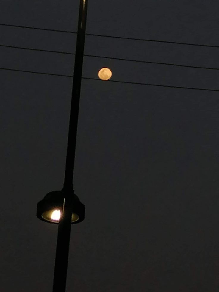 a street light with the moon in the background