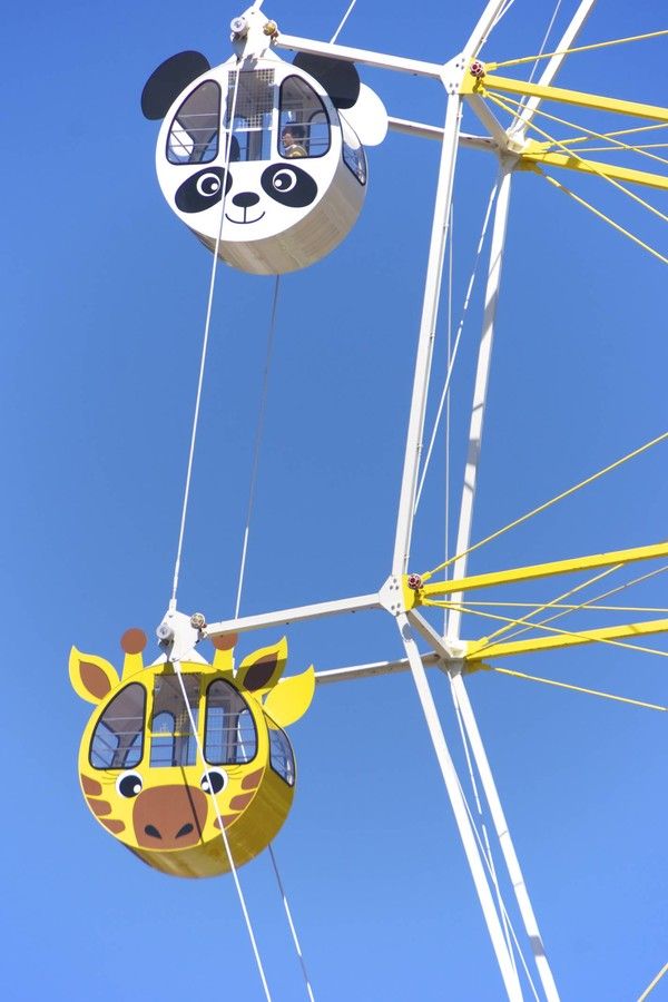 two giraffes hanging from the side of a ferris wheel