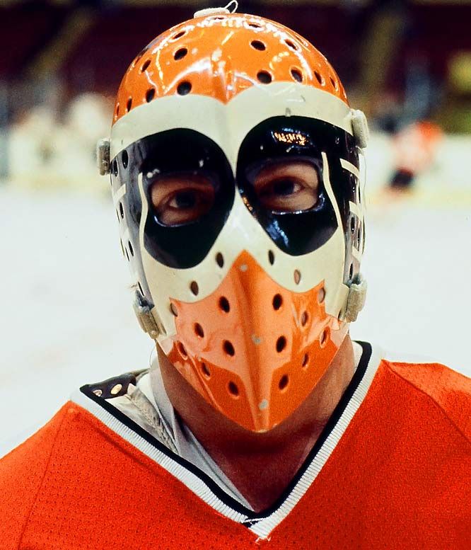 a man in an orange hockey uniform wearing a mask with holes on his face and eyes