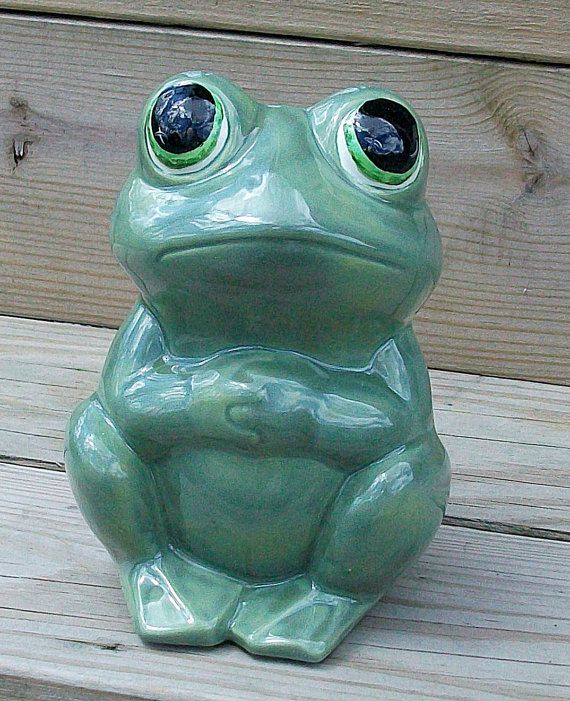 a green frog sitting on top of a wooden bench