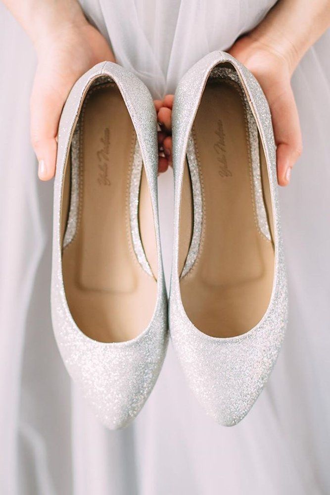 the brides wedding shoes are being held up by her hands in front of their dress