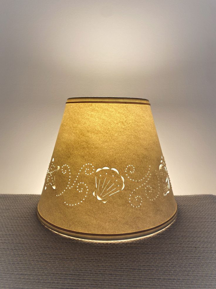 a gold lamp shade with the word seas written in cursive writing on it