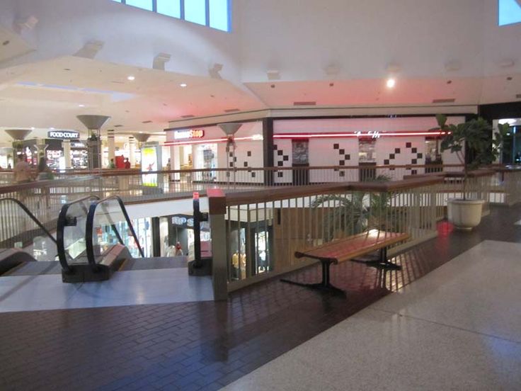 an empty shopping mall with benches and escalators