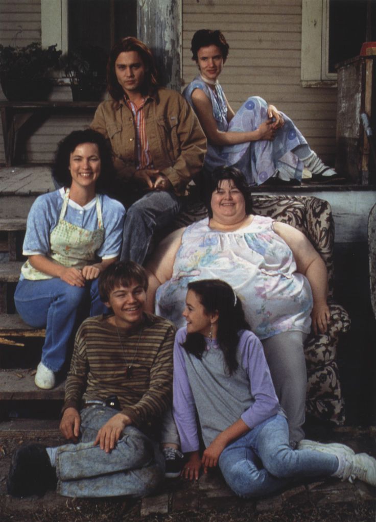 a group of people sitting on the steps in front of a house, posing for a photo