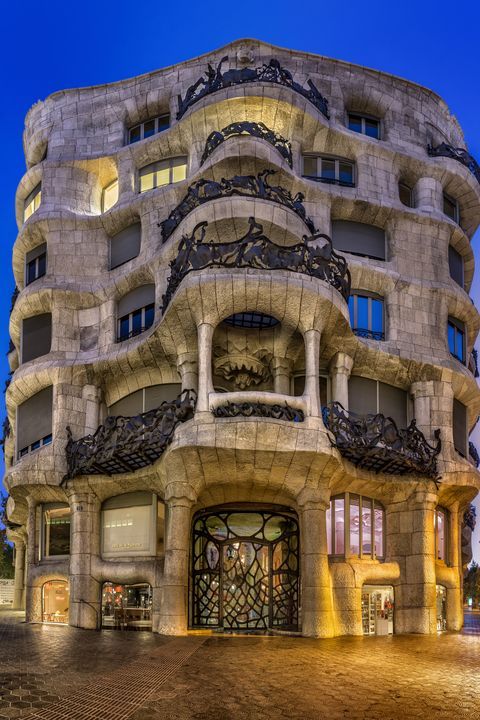 an artistic building is lit up at night with lights on the windows and balconies