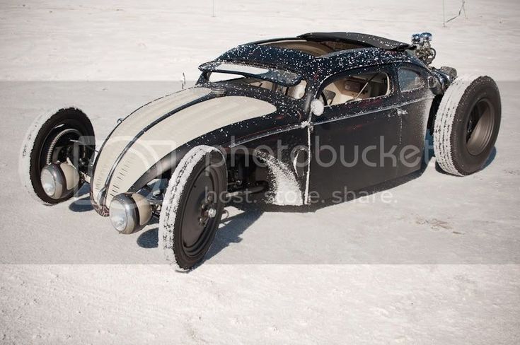 an old model car is parked in the snow on top of some snow covered ground