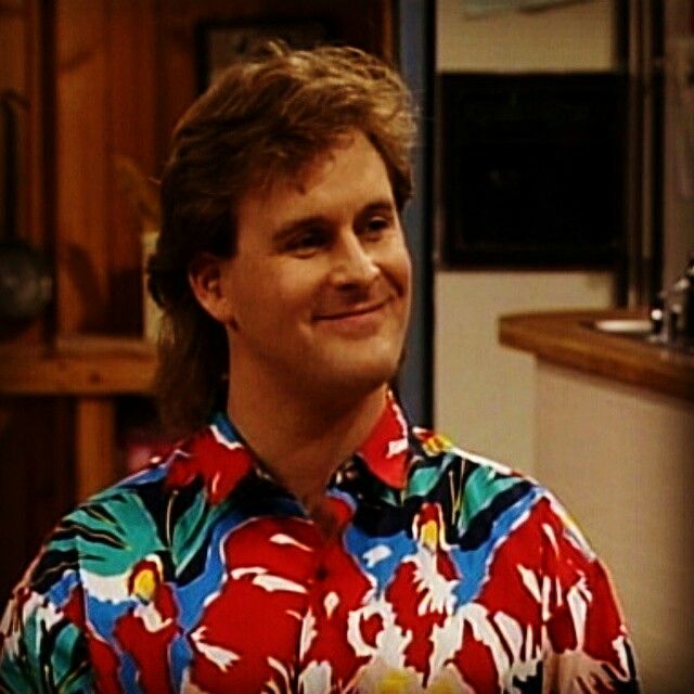 the young man is wearing a colorful shirt and standing in front of a kitchen sink