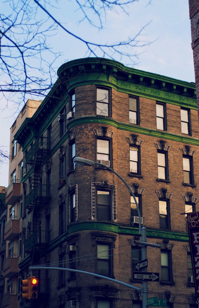 an old brick building with many windows on the top floor and green trim around the corner