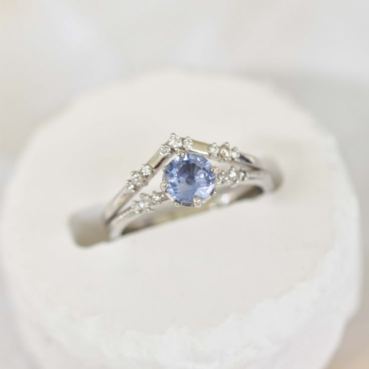 a white gold ring with an oval blue topazte surrounded by small round diamonds