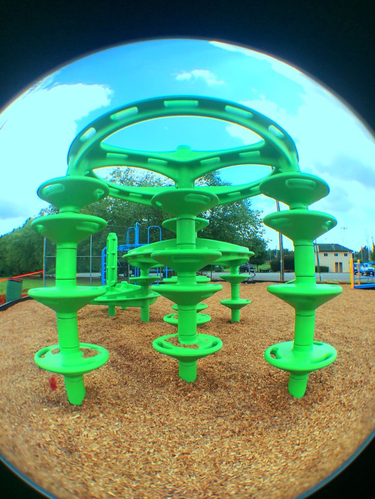 a green playground structure in the middle of a park