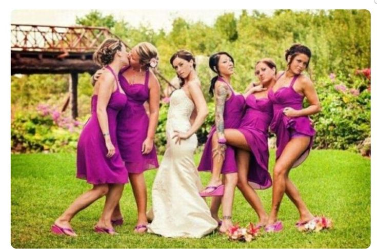 a group of women in purple dresses standing next to each other on top of grass