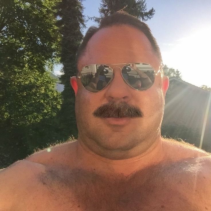 a shirtless man with sunglasses and a moustache is posing for the camera