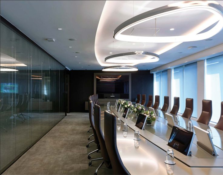 an empty conference room with long tables and chairs in front of large glass walls that have lights on them