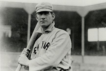 an old black and white photo of a baseball player holding a bat in his hands