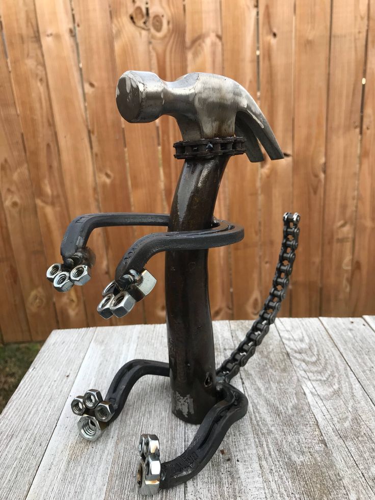 a metal sculpture on top of a wooden table next to a fence and wood planks