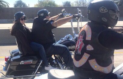 two people riding on the back of a motorcycle with their helmets on and one person wearing a helmet