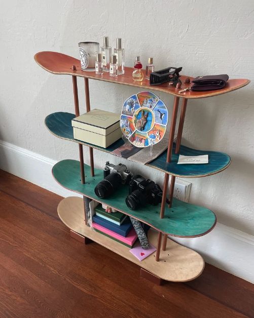 three tiered shelf with books, camera and other items on it in front of a white wall