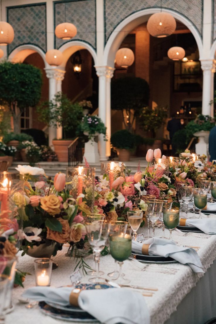 a long table is set with candles and flowers for a formal dinner in an elegant setting