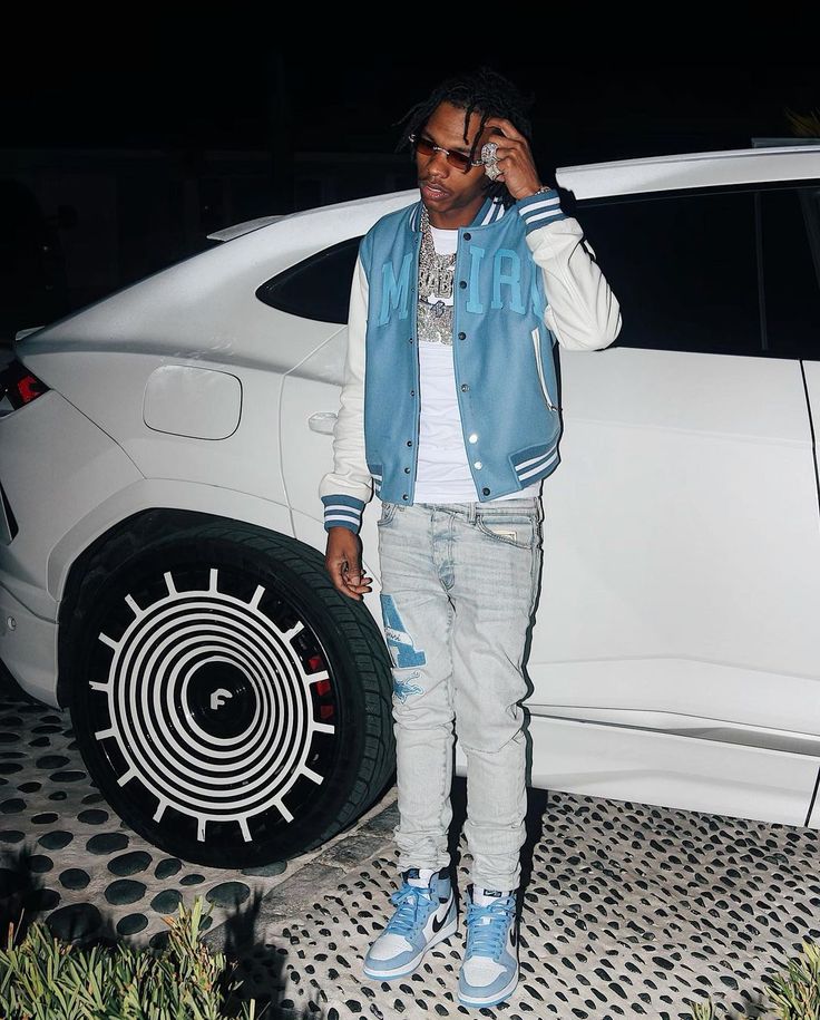 a man standing next to a white car talking on a cell phone